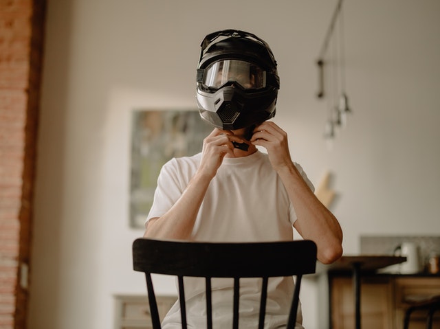 A man wearing a black painted motorcycle helmet
