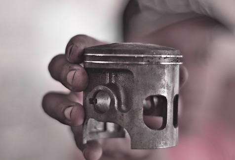 A man holding a piston with piston rings