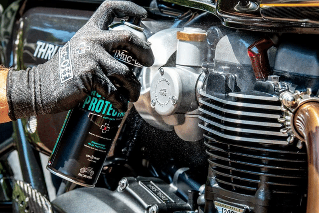A man spraying maintenance spray on motorcycle