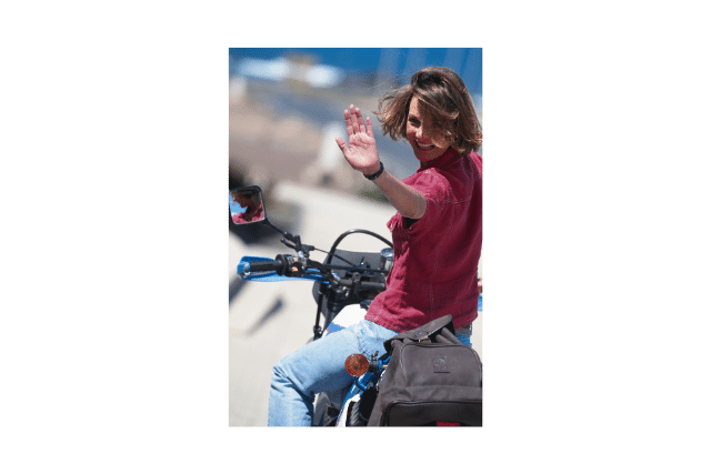 A woman on a motorcycle waving