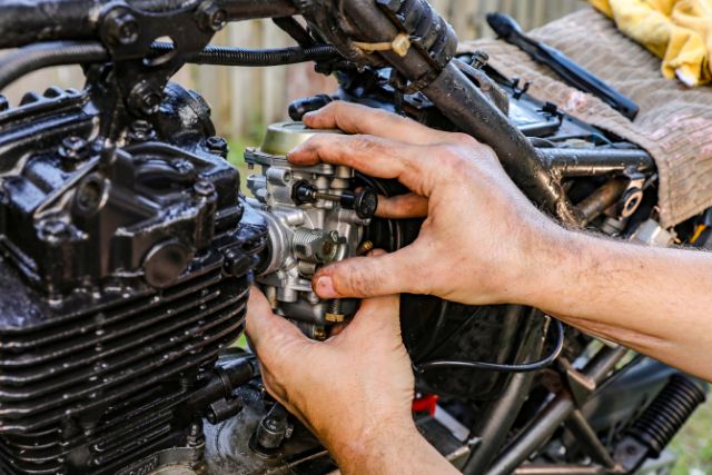 A man fitting carburetor in a motorcycle