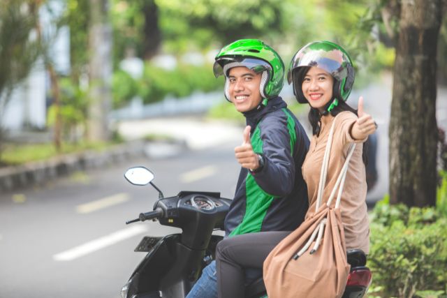 Two People on a scooter giving thumbs up