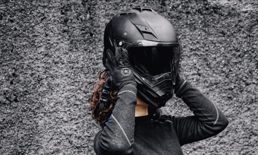 A woman rider removing a heavy helmet from her head