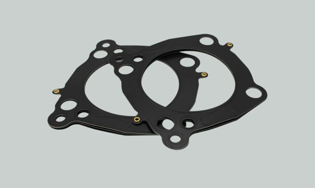 Motorcycle engine cylinder gaskets on a grey background