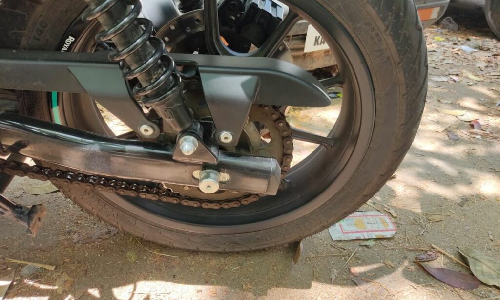 Motorcycle rear wheel with chain, suspension, and axle bolt