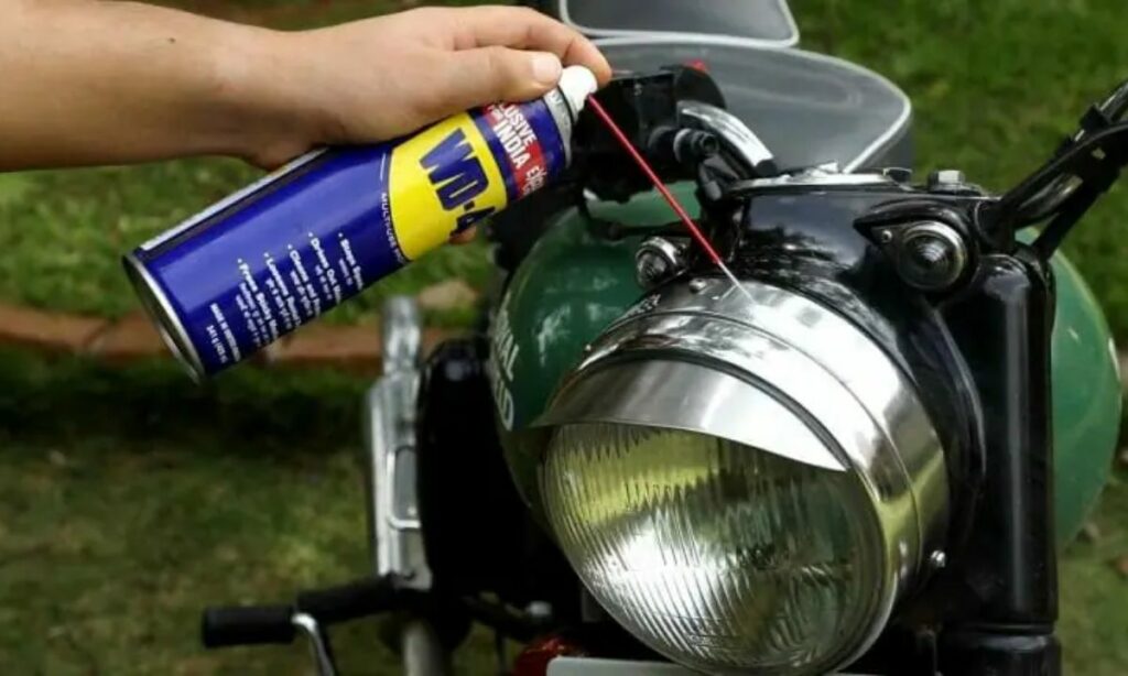 A guy spraying WD-40 on motorcycle headlight