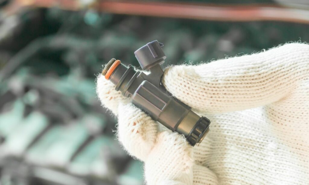 A white-gloved hand holding a fuel injector