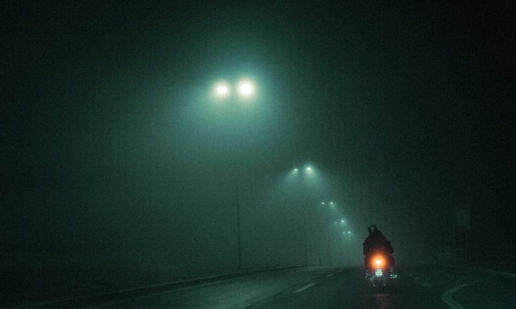 Motorcycle riding on foggy road at night