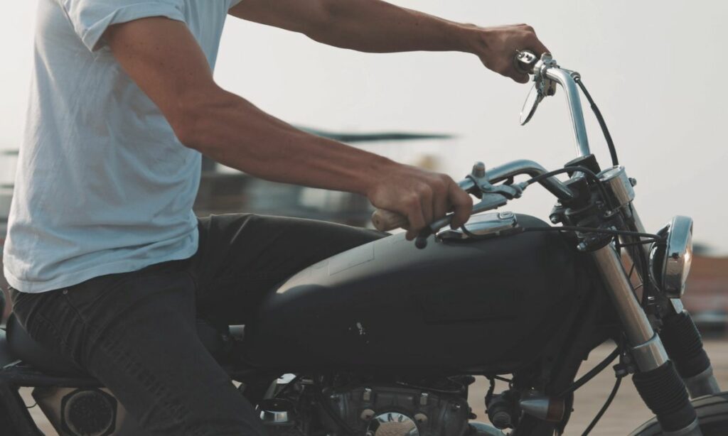 A guy riding motorcycle with his hands gripping the handlebar