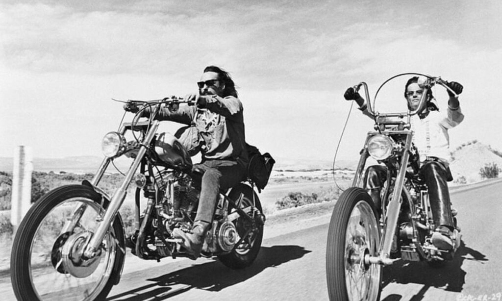 2 riders riding a bobber or a chopper motorcycle