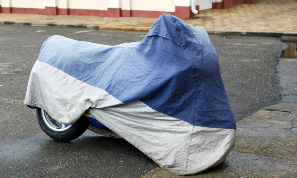 A blue bike cover covering a motorcycle