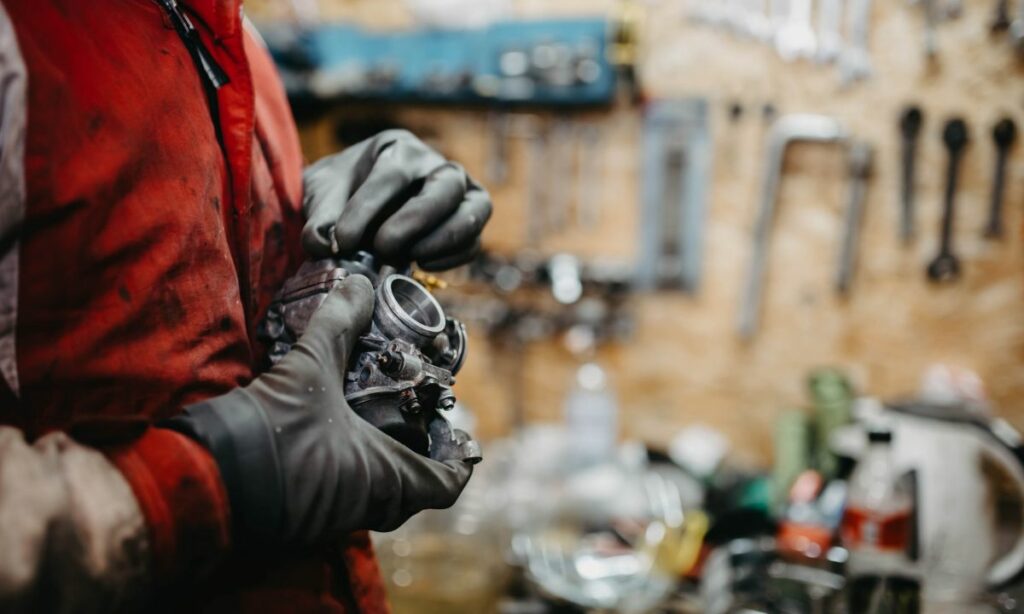 A motorcycle mechanic working on the carburetor in a garage