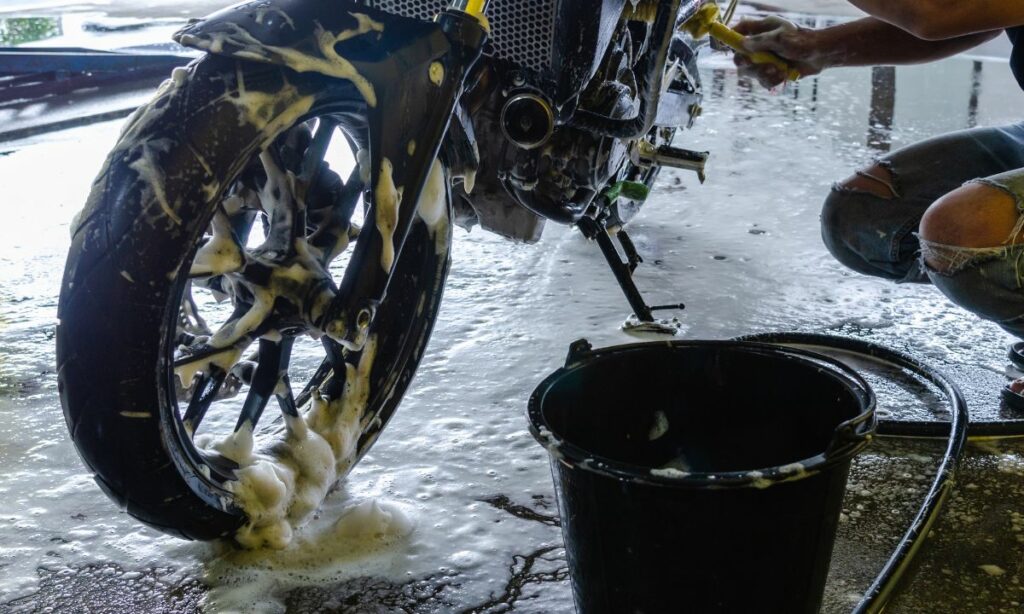 A guy washing a motorcycle with soap water