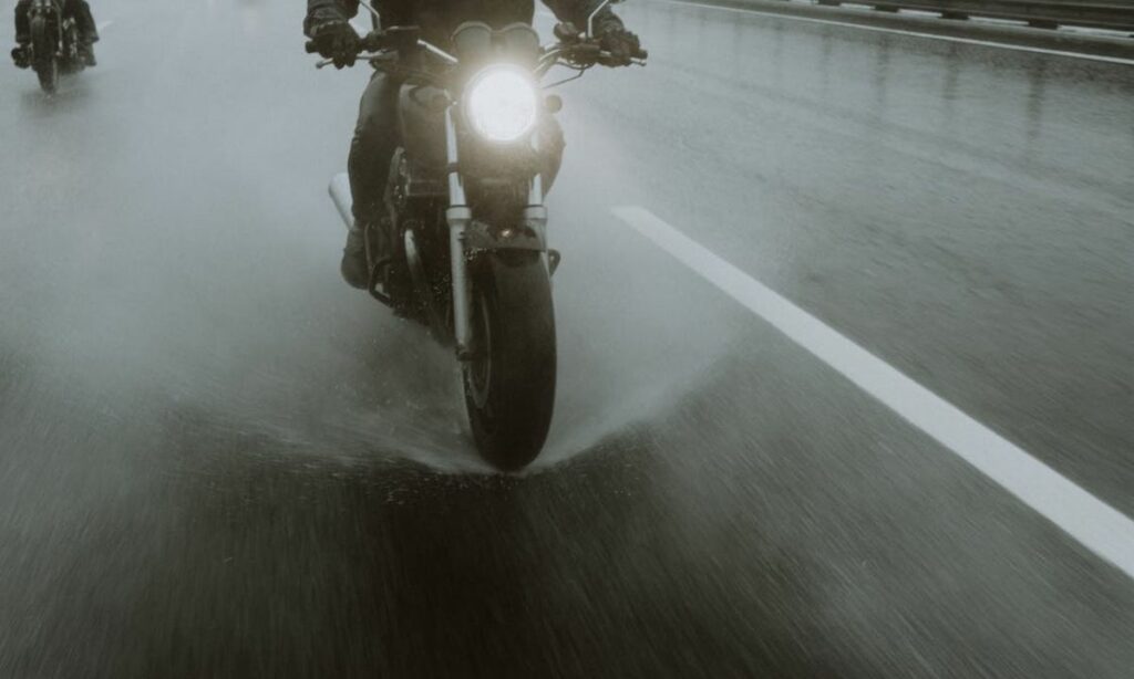 A motorcycle splashing water on the road due to rain