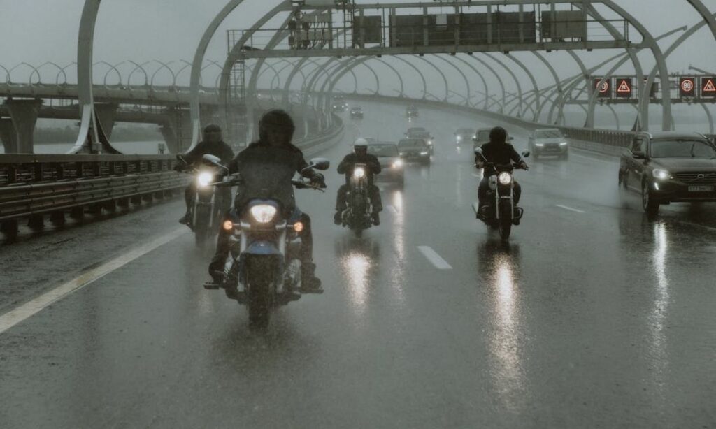 Motorcycle riders riding bikes amidst heacy rains