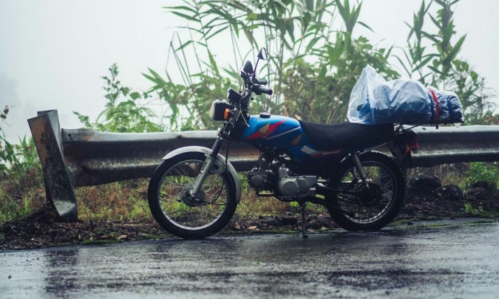 A blue Honda parked on road while raining