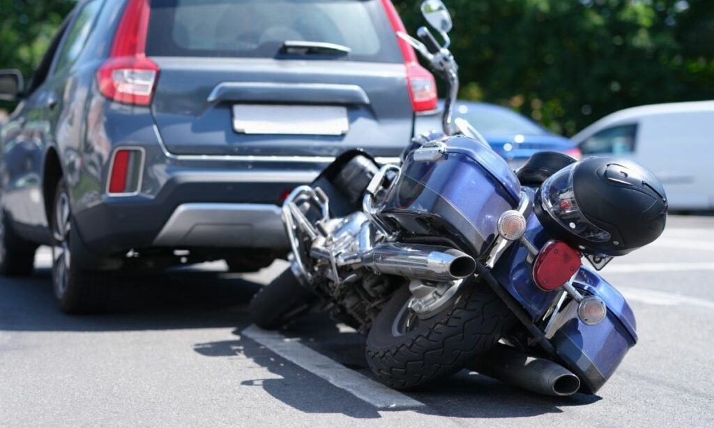Motorcycle toppled down behind a car