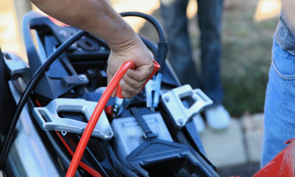 A guy charging a motorcycle battery